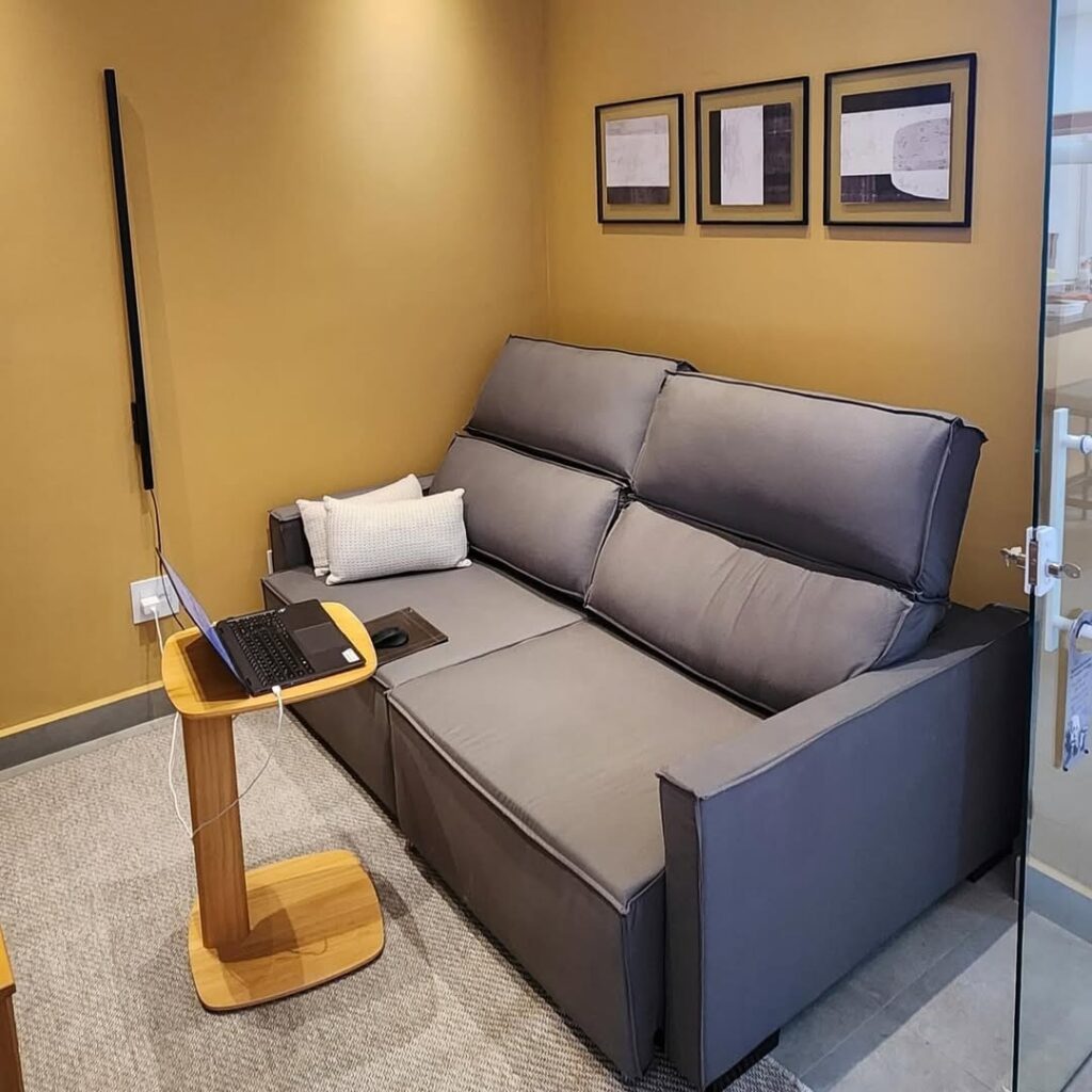 Reforma de sofá retrátil cinza realizada pela Magnífico Estofados na Barra da Tijuca, Rio de Janeiro. Imagem mostrando o acabamento de alta qualidade em um ambiente moderno, ideal para serviços de estofador profissional e renovação de estofados de luxo.