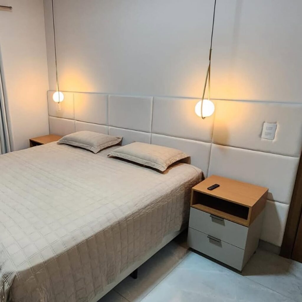 Detalhe técnico de cabeceira modular branca personalizada. Exemplo de acabamento artesanal em tecido de alta qualidade para decoração de quartos de luxo, com foco na precisão das costuras e volume do estofado.