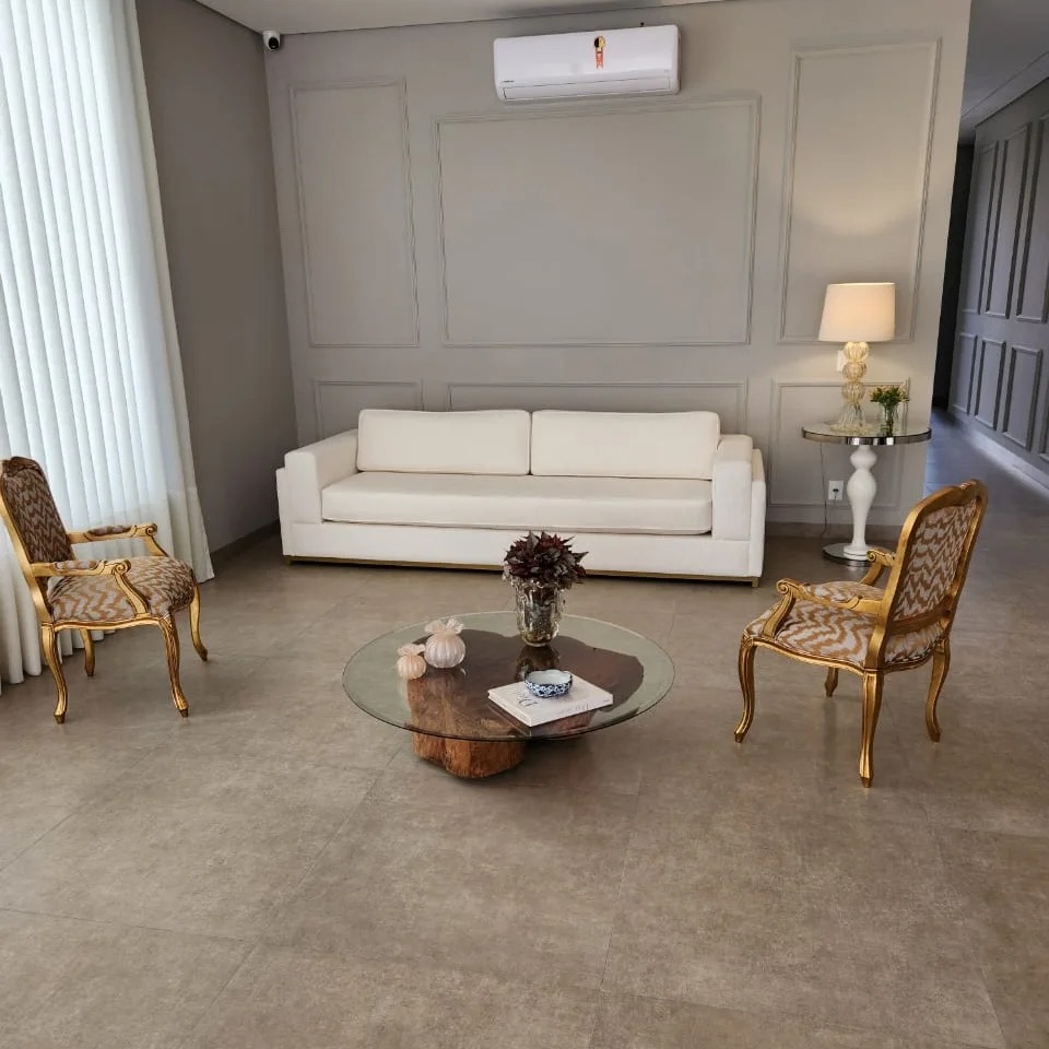 Reforma de estofados de luxo realizada no condomínio Península, Barra da Tijuca. Sala de estar decorada com sofá branco e poltronas clássicas restauradas pela Magnífico Estofados RJ, especialista em tapeçaria de alto padrão.